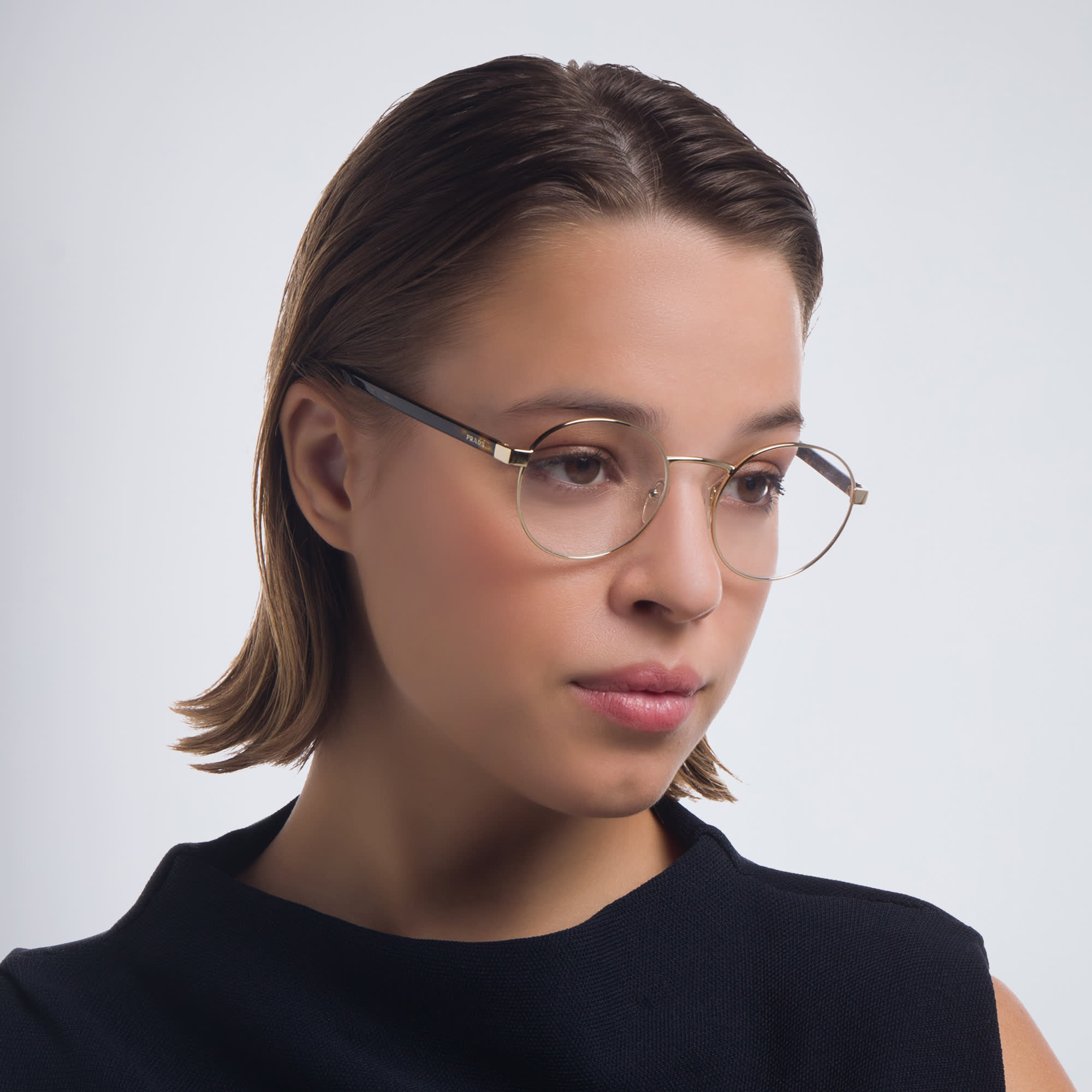 Shop PRADA Round Eyeglasses in Pale Gold online.